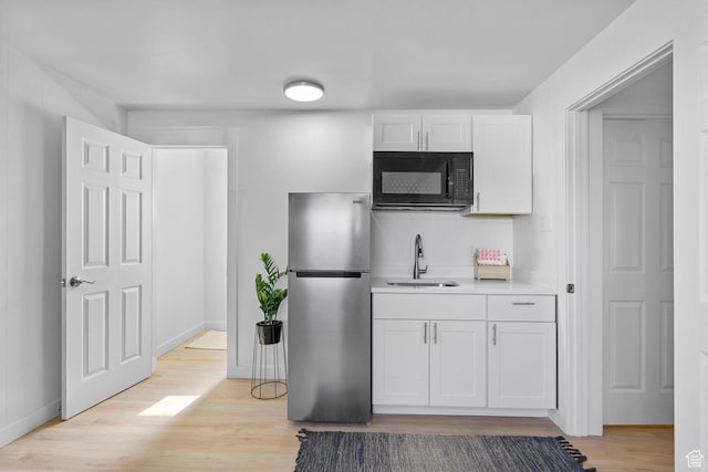 672 Nelson Ave, Tooele, UT 84074 - kitchen featuring freestanding refrigerator, black microwave, a sink, light wood-style flooring, and white cabinetry
