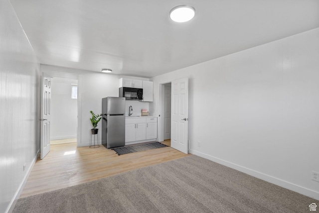 672 Nelson Ave, Tooele, UT 84074 - kitchen with freestanding refrigerator, black microwave, a sink, baseboards, and white cabinetry