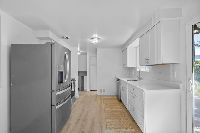 672 Nelson Ave, Tooele, UT 84074 - kitchen featuring appliances with stainless steel finishes, a sink, light countertops, white cabinets, and light wood-style floors