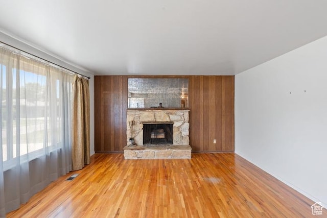 1460 Canyon Dr, South Weber, UT 84405 - unfurnished living room featuring a stone fireplace, light wood finished floors, wooden walls, and baseboards