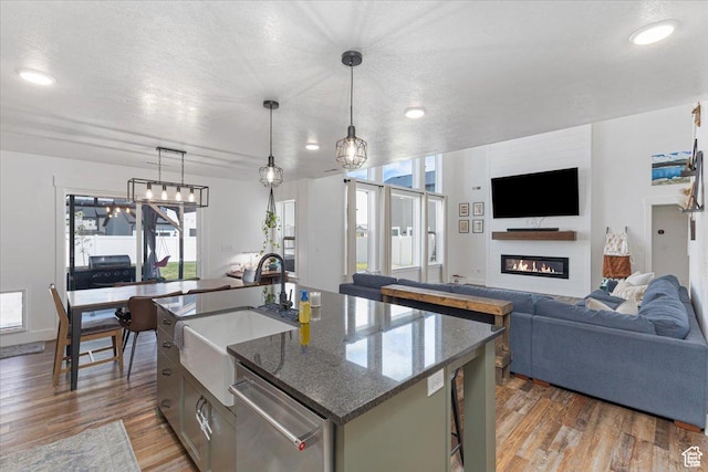 325 W 3170 S, Nibley, UT 84321 - kitchen with a sink, stainless steel dishwasher, wood finished floors, a glass covered fireplace, and dark stone counters