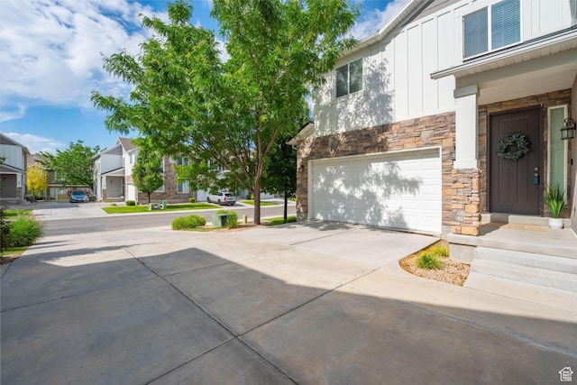 244 E Cordoba Dr, Saratoga Springs, UT 84045 - property entrance with stone siding, board and batten siding, an attached garage, concrete driveway, and a residential view