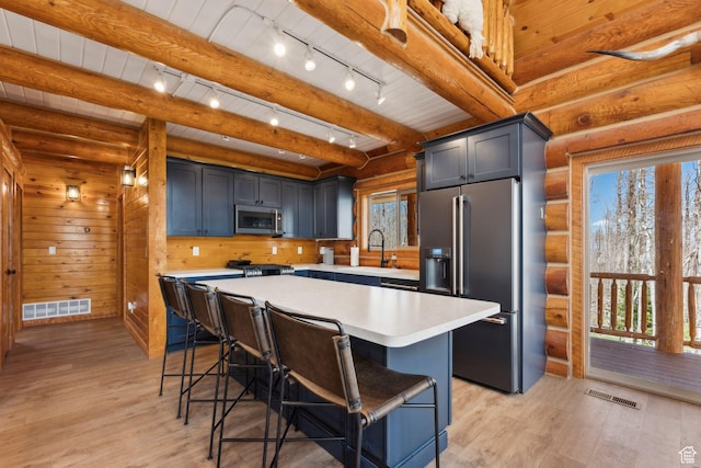 1085 Moose Hollow Rd, Robertson, WY 82944 - kitchen with appliances with stainless steel finishes, light countertops, a kitchen bar, light wood finished floors, and beam ceiling