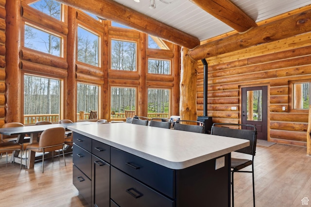1085 Moose Hollow Rd, Robertson, WY 82944 - kitchen with light countertops, dark cabinetry, a wood stove, beam ceiling, and log walls