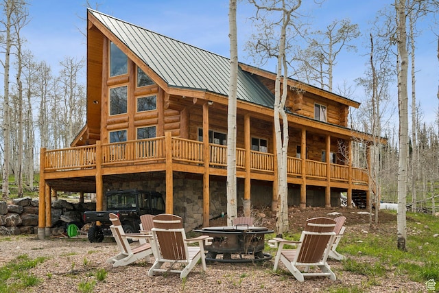 1085 Moose Hollow Rd, Robertson, WY 82944 - rear view of house with an outdoor fire pit, log siding, a deck, metal roof, and stone siding