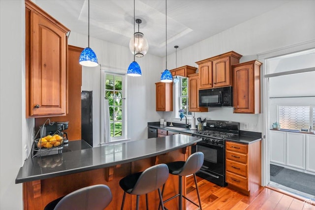 479 N Main St, Farmington, UT 84025 - kitchen with black appliances, light wood-type flooring, a peninsula, dark countertops, and a sink