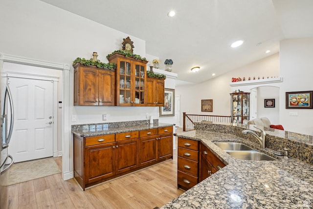 9451 S Peaceful View Way S, Jordan, UT 84095 - kitchen featuring vaulted ceiling, light wood-style floors, a sink, glass insert cabinets, and dark stone counters