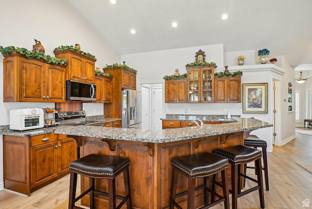 9451 S Peaceful View Way S, Jordan, UT 84095 - kitchen with stainless steel appliances, glass insert cabinets, light wood-style flooring, brown cabinets, and recessed lighting