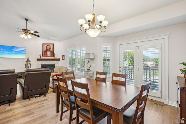 9451 S Peaceful View Way S, Jordan, UT 84095 - dining area featuring light wood-type flooring, a chandelier, a fireplace, healthy amount of natural light, and vaulted ceiling