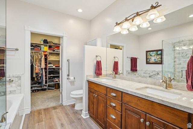9451 S Peaceful View Way S, Jordan, UT 84095 - full bathroom with double vanity, toilet, a garden tub, wood finished floors, and a spacious closet