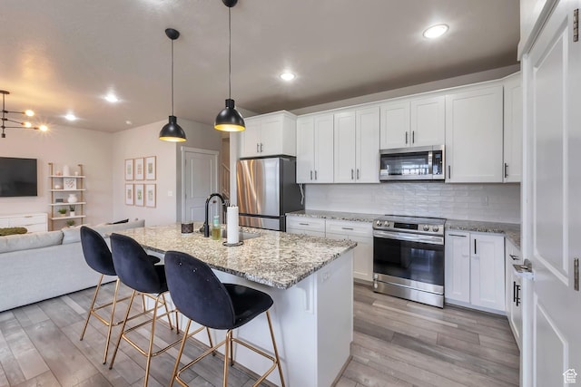 945 W Mckenna Rd, Bluffdale, UT 84065 - kitchen featuring appliances with stainless steel finishes, a sink, open floor plan, light wood-style flooring, and decorative backsplash