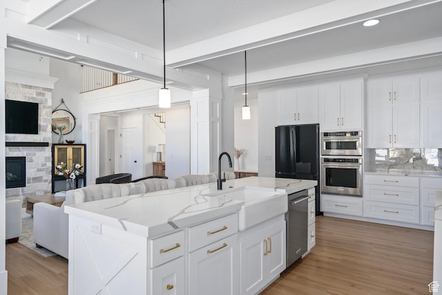 648 W 400 N, Mapleton, UT 84664 - kitchen with open floor plan, a sink, stainless steel appliances, a fireplace, and white cabinetry