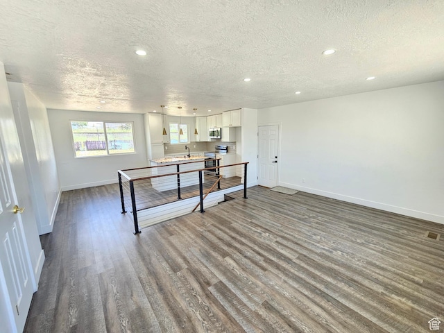 8181 W Danbury Dr, Magna, UT 84044 - kitchen featuring stainless steel appliances, a textured ceiling, baseboards, dark wood-style flooring, and white cabinets