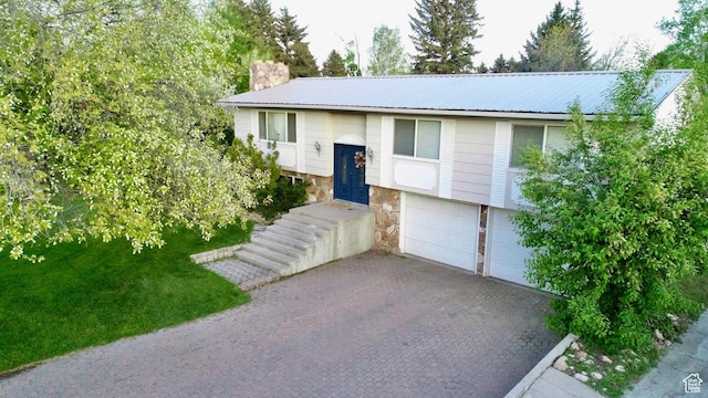 130 Cascade Quey St, Soda Springs, ID 83276 - bi-level home featuring a garage, driveway, a chimney, stone siding, and metal roof