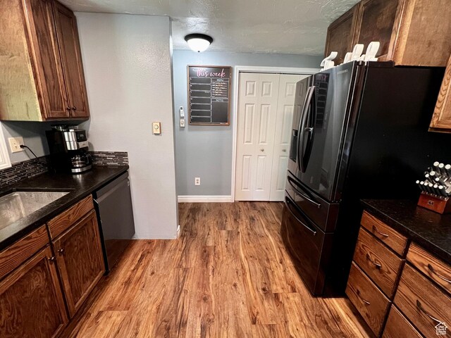 130 Cascade Quey St, Soda Springs, ID 83276 - kitchen featuring light wood finished floors, stainless steel dishwasher, black refrigerator with ice dispenser, baseboards, and a textured ceiling