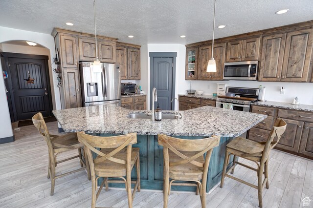 343 W Deer Creek Trl, Salem, UT 84653 - kitchen featuring appliances with stainless steel finishes, a sink, arched walkways, a breakfast bar, and hanging light fixtures