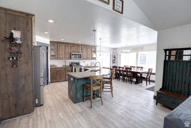 343 W Deer Creek Trl, Salem, UT 84653 - kitchen featuring stainless steel appliances, brown cabinets, a breakfast bar, glass insert cabinets, and light wood-style flooring
