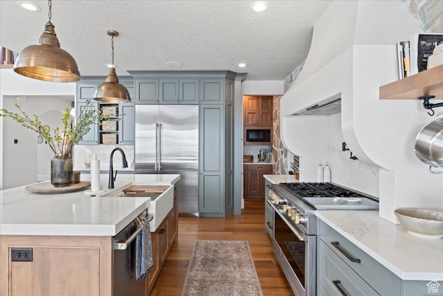 3651 N 200 E, North Ogden, UT 84414 - kitchen featuring built in appliances, a sink, a kitchen island with sink, dark wood finished floors, and decorative light fixtures