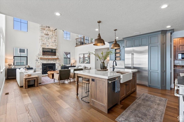 3651 N 200 E, North Ogden, UT 84414 - kitchen featuring appliances with stainless steel finishes, a textured ceiling, light countertops, a fireplace, and a center island with sink