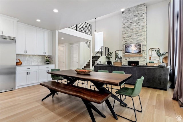 325 N 1200 E, American Fork, UT 84003 - dining room featuring light wood-style floors, a stone fireplace, stairway, recessed lighting, and a towering ceiling