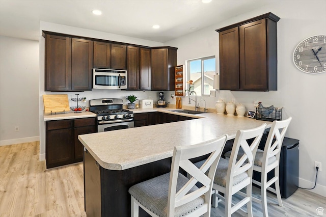 5186 W Hedgerose Dr S, Herriman, UT 84096 - kitchen featuring stainless steel appliances, light countertops, dark brown cabinetry, a kitchen bar, and a peninsula