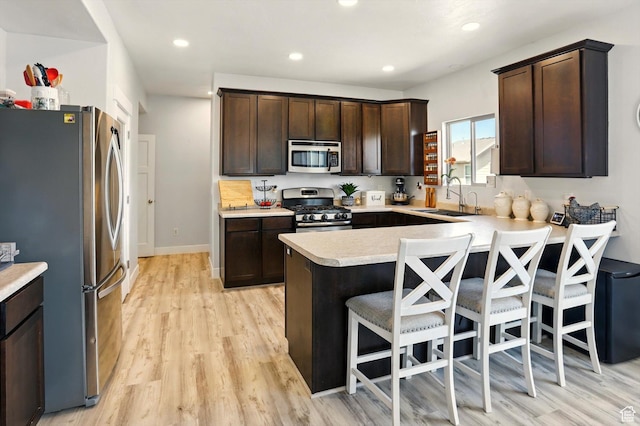 5186 W Hedgerose Dr S, Herriman, UT 84096 - kitchen with appliances with stainless steel finishes, a sink, a peninsula, dark brown cabinets, and recessed lighting