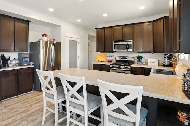 5186 W Hedgerose Dr S, Herriman, UT 84096 - kitchen featuring appliances with stainless steel finishes, a sink, light countertops, dark brown cabinetry, and light wood-style flooring