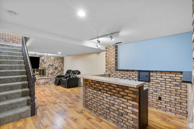 4589 S Trojan Dr, West Valley City, UT 84120 - bar area featuring stairway, light wood-type flooring, a stone fireplace, and rail lighting