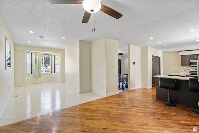 4589 S Trojan Dr, West Valley City, UT 84120 - living room featuring a textured ceiling, a ceiling fan, light wood-style floors, recessed lighting, and baseboards