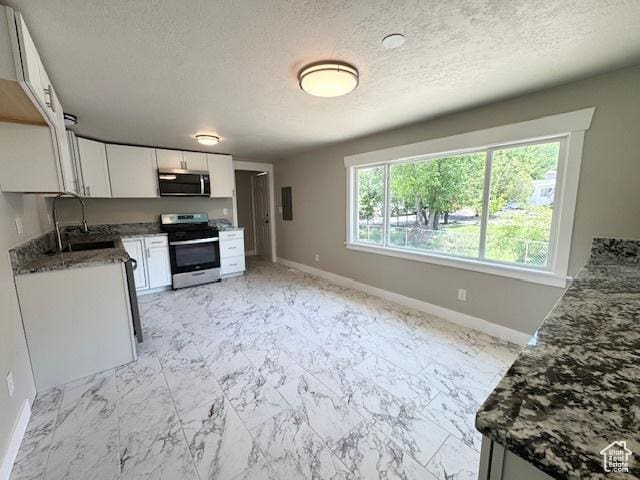 933 E 1150 N, Ogden, UT 84404 - kitchen featuring stainless steel appliances, a sink, baseboards, white cabinets, and a textured ceiling
