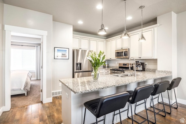 1722 W Naxos Ln, South Jordan, UT 84095 - kitchen featuring stainless steel appliances, baseboards, a peninsula, dark wood-style flooring, and light stone countertops