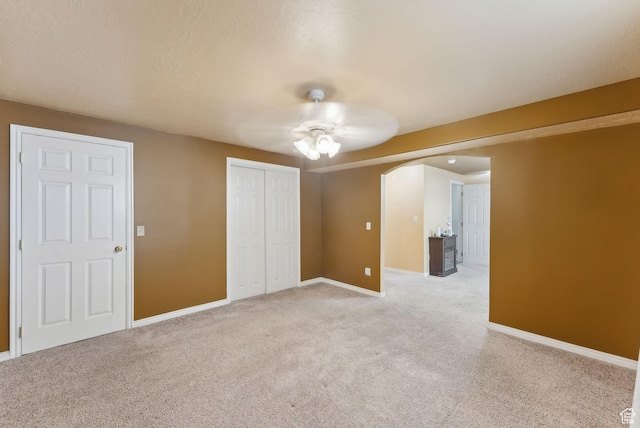 192 Starboard Ln, Stansbury Park, UT 84074 - unfurnished bedroom featuring arched walkways, light carpet, a closet, baseboards, and a ceiling fan