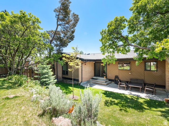 4968 S Partridge Way E, Ogden, UT 84403 - rear view of property with a lawn, solar panels, brick siding, a patio, and roof with shingles