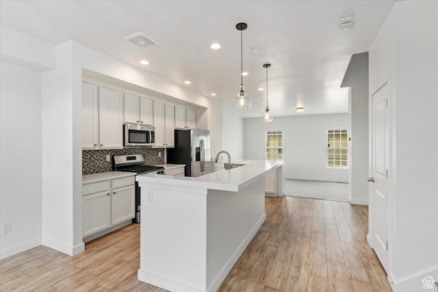 5377 W Bowstring Way S, Jordan, UT 84009 - kitchen featuring appliances with stainless steel finishes, light wood-type flooring, tasteful backsplash, a center island with sink, and recessed lighting