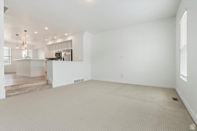 5377 W Bowstring Way S, Jordan, UT 84009 - unfurnished living room with recessed lighting, light carpet, baseboards, and a sink