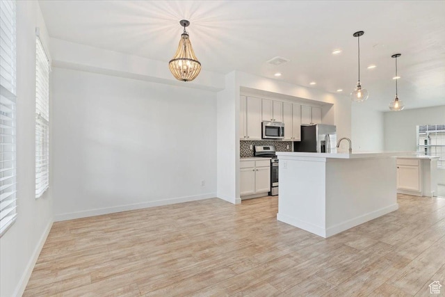 5377 W Bowstring Way S, Jordan, UT 84009 - kitchen with appliances with stainless steel finishes, light wood finished floors, decorative backsplash, a sink, and a chandelier