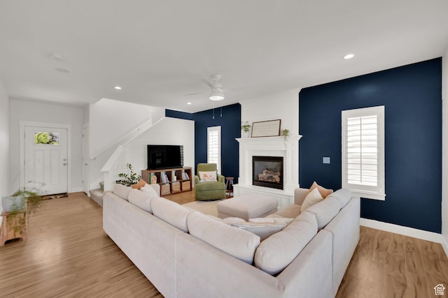 7859 N Sagebrush Ln, Eagle Mountain, UT 84005 - living room featuring a glass covered fireplace, ceiling fan, light wood-type flooring, stairs, and baseboards