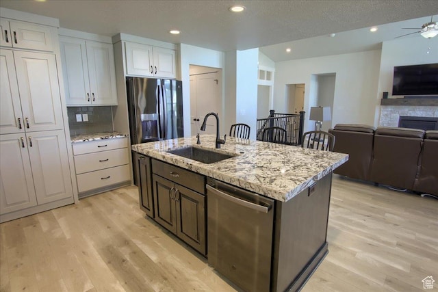 4016 W 625 S, West Point, UT 84015 - kitchen with appliances with stainless steel finishes, a sink, open floor plan, light wood-style flooring, and a textured ceiling
