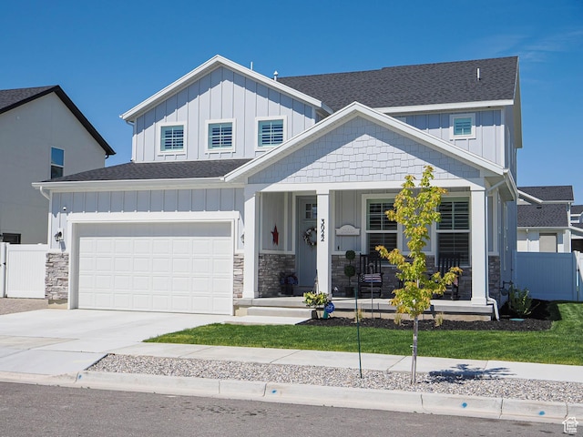 3022 S Shoreline Dr W, Syracuse, UT 84075 - view of front of house featuring roof with shingles, board and batten siding, a porch, driveway, and stone siding