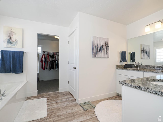 3022 S Shoreline Dr W, Syracuse, UT 84075 - full bathroom featuring wood finished floors, vanity, a garden tub, baseboards, and a spacious closet