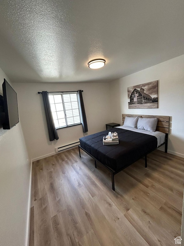 1350 W 150 N Unit 22, Vernal, UT 84078 - bedroom featuring wood finished floors, a baseboard radiator, a textured ceiling, and baseboards