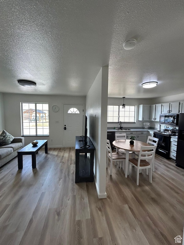 1350 W 150 N Unit 22, Vernal, UT 84078 - kitchen featuring black appliances, a textured ceiling, light wood finished floors, a sink, and baseboards