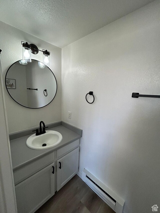 1350 W 150 N Unit 22, Vernal, UT 84078 - bathroom featuring a baseboard radiator, wood finished floors, vanity, and a textured ceiling