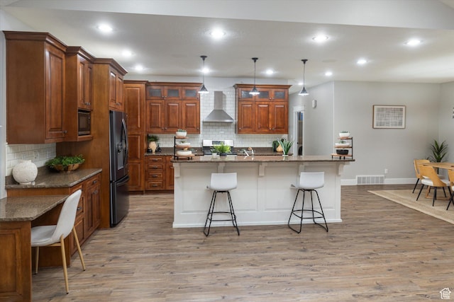1697 S 3200 W, Logan, UT 84321 - kitchen featuring wall chimney range hood, black appliances, a breakfast bar area, backsplash, and recessed lighting