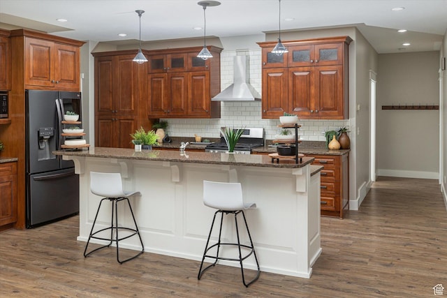 1697 S 3200 W, Logan, UT 84321 - kitchen with fridge with ice dispenser, wall chimney range hood, a breakfast bar, decorative backsplash, and gas stove