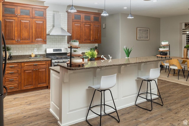 1697 S 3200 W, Logan, UT 84321 - kitchen with wall chimney exhaust hood, gas stove, light wood-style floors, decorative backsplash, and recessed lighting