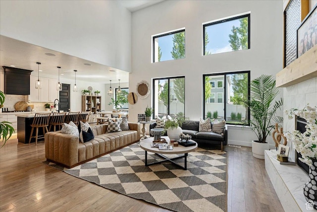 144 E 150 N, Vineyard, UT 84059 - living room with light wood-type flooring, plenty of natural light, a tile fireplace, and a towering ceiling
