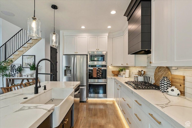 144 E 150 N, Vineyard, UT 84059 - kitchen with appliances with stainless steel finishes, a sink, wall chimney range hood, light wood finished floors, and decorative light fixtures