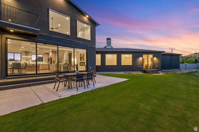 12719 S Outlaw Pl E, Draper, UT 84020 - back of house at dusk with a balcony, a lawn, a patio, and a chimney