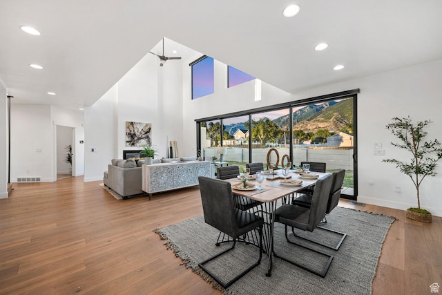 12719 S Outlaw Pl E, Draper, UT 84020 - dining room featuring baseboards, light wood-style floors, recessed lighting, a towering ceiling, and a glass covered fireplace